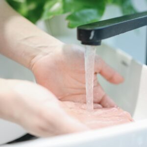 Hands washing under a modern bathroom faucet, emphasizing hygiene and cleanliness.