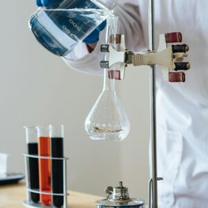 Scientist pouring liquid into a flask in a laboratory setting for research.