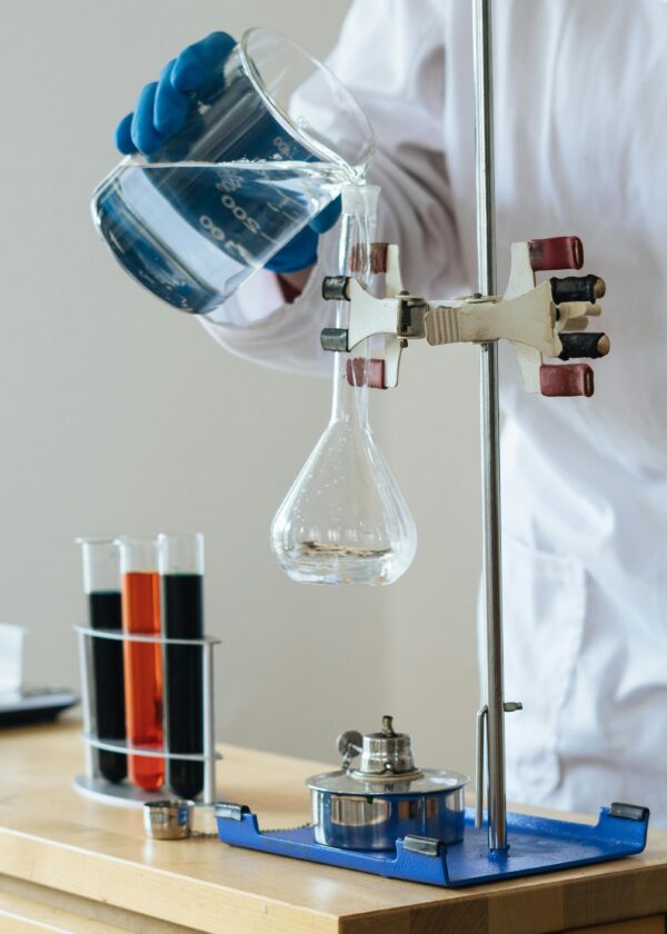 Scientist pouring liquid into a flask in a laboratory setting for research.