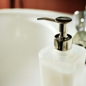 Close-up of a modern soap dispenser beside a sink in a clean bathroom.