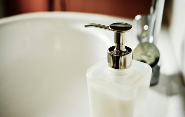 Close-up of a modern soap dispenser beside a sink in a clean bathroom.
