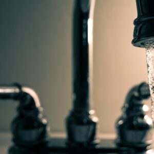 A detailed shot of water flowing from a steel faucet, ideal for themes on cleanliness or plumbing.